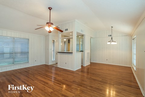 A spacious room with wooden floors and a ceiling fan.