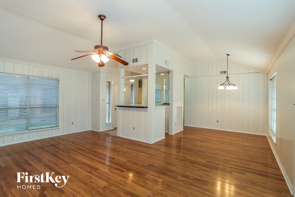 A spacious room with wooden floors and a ceiling fan.