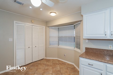 A kitchen with white cabinets and a brown countertop.