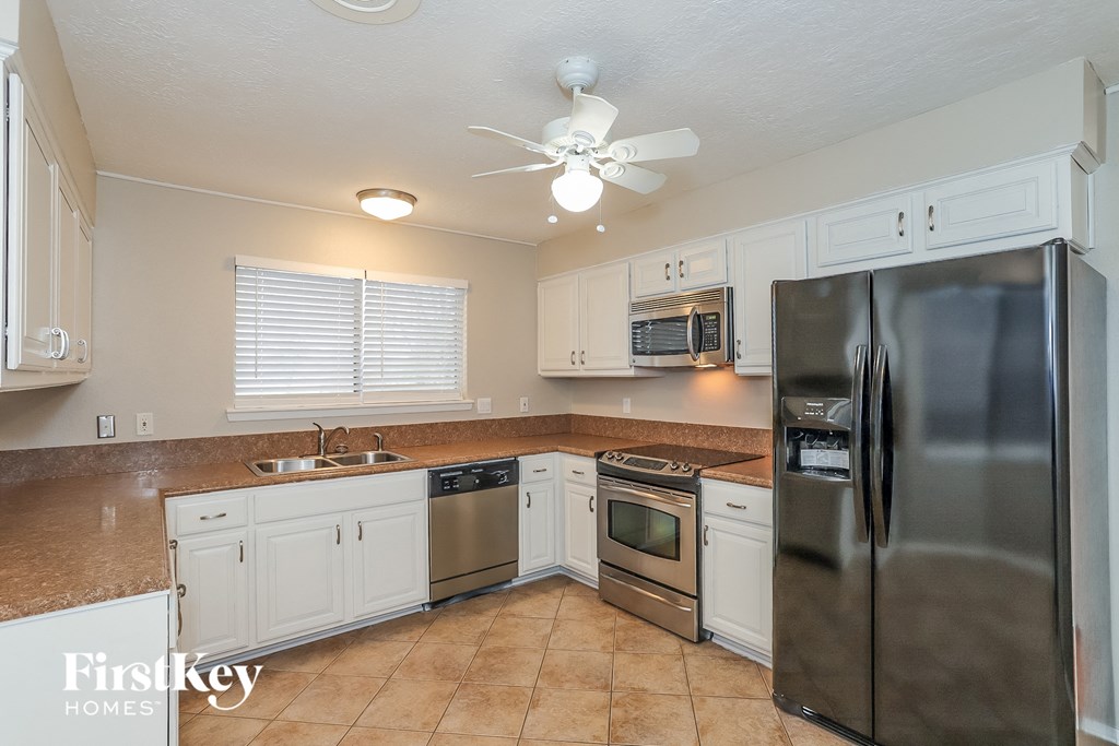 A kitchen with a refrigerator, sink, and microwave.