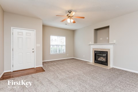 A spacious living room with a fireplace and a ceiling fan.