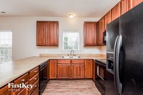 A kitchen with wooden cabinets and a black refrigerator.