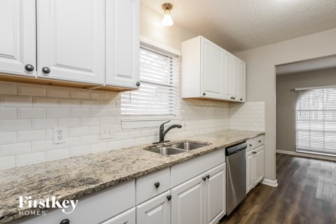 A kitchen with white cabinets and a granite countertop.