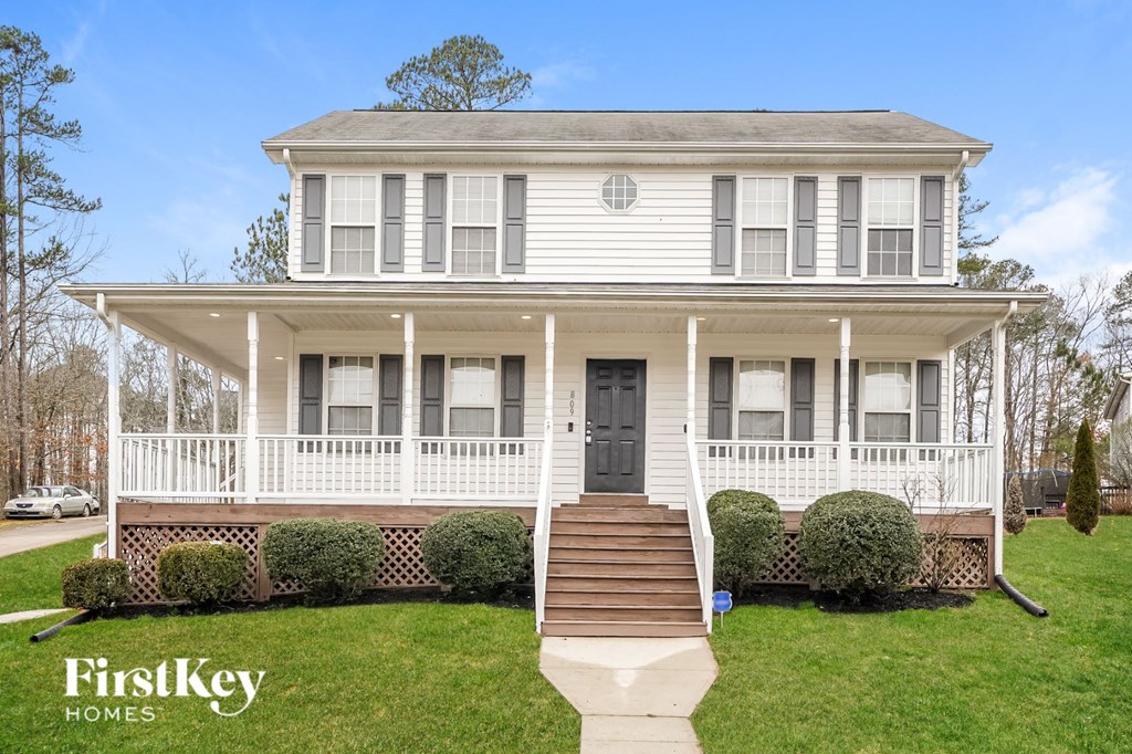A white two-story house with a porch and a black door.