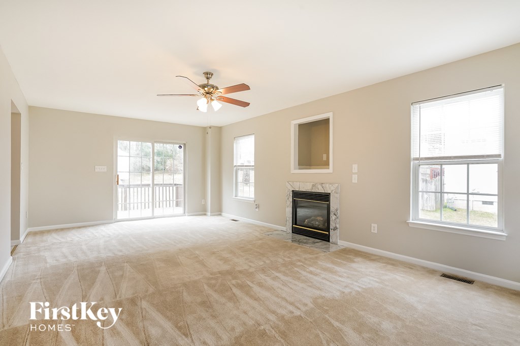 A spacious living room with a fireplace and a ceiling fan.