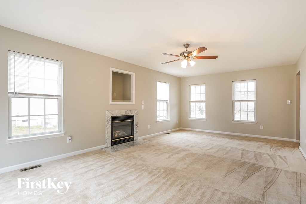 A spacious room with a fireplace and a ceiling fan.