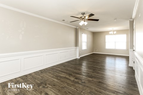 A spacious room with wooden floors and a ceiling fan.