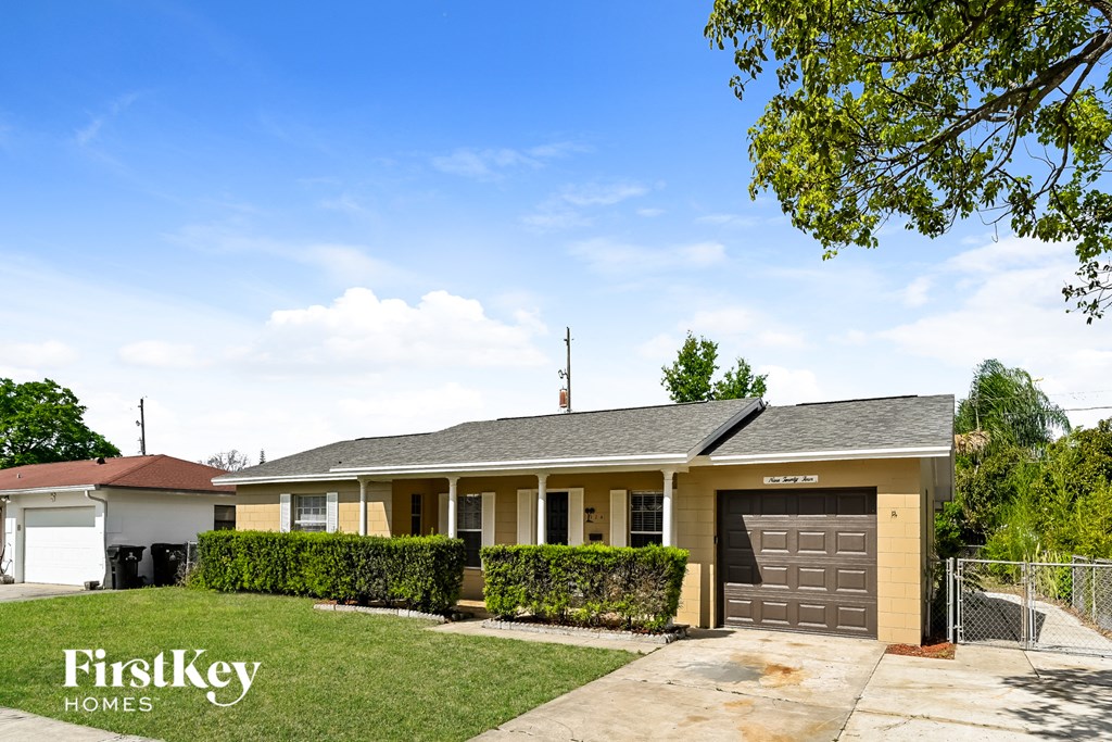 A house with a garage and a tree in front.