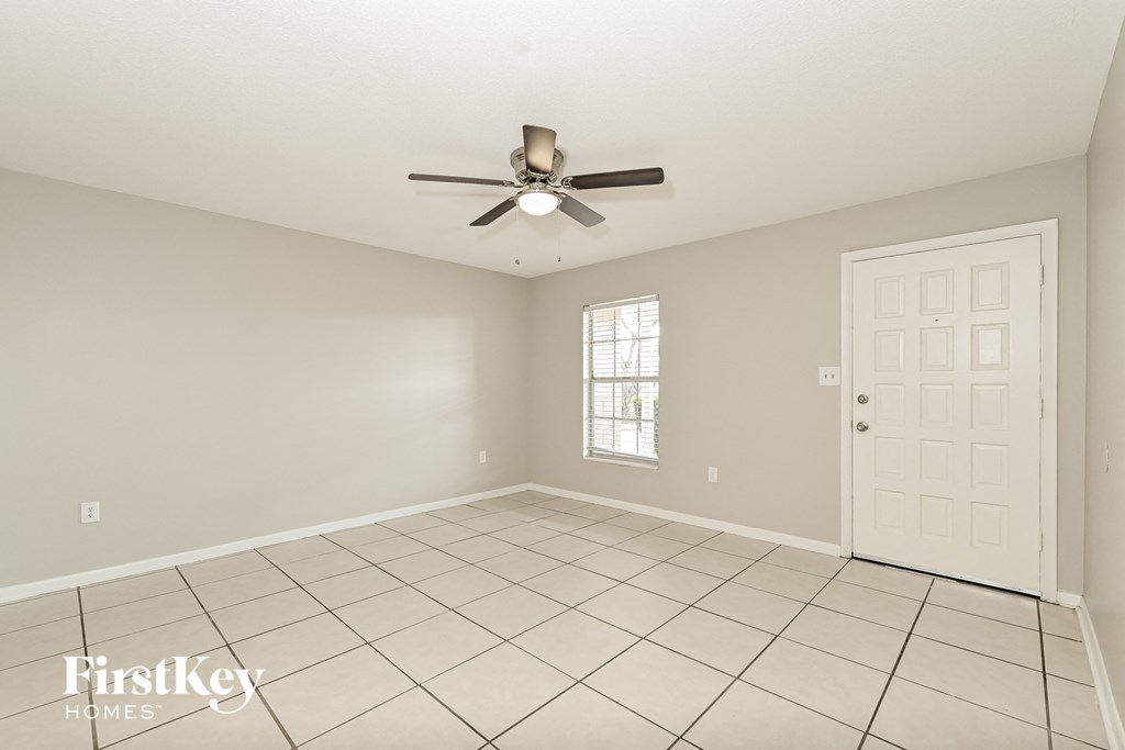 A room with a fan, tile floor, and a door.