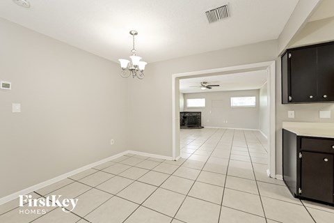 A spacious room with a chandelier and a flat screen TV mounted on the wall.