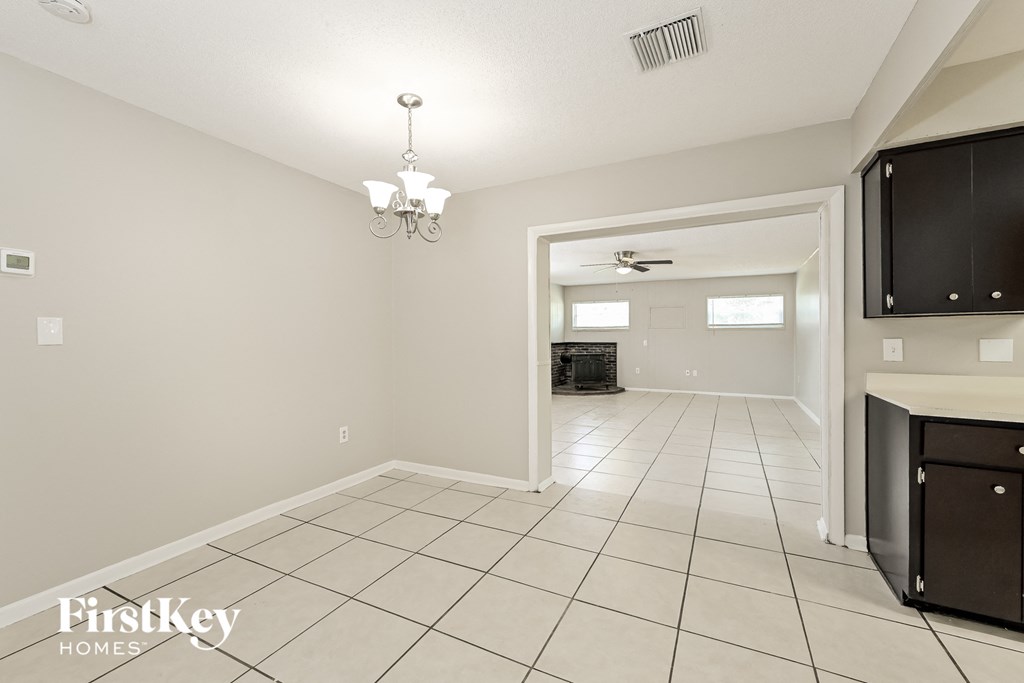 A spacious room with a chandelier and a flat screen TV mounted on the wall.