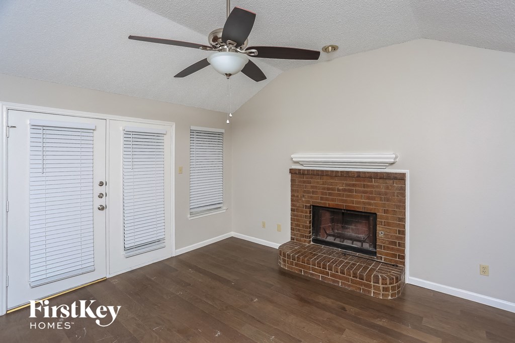 a living room with a brick fireplace and a ceiling fan