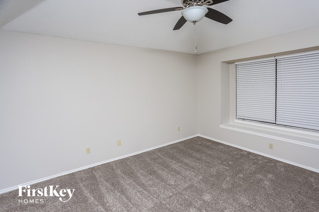 the living room of an empty house with a ceiling fan and a window