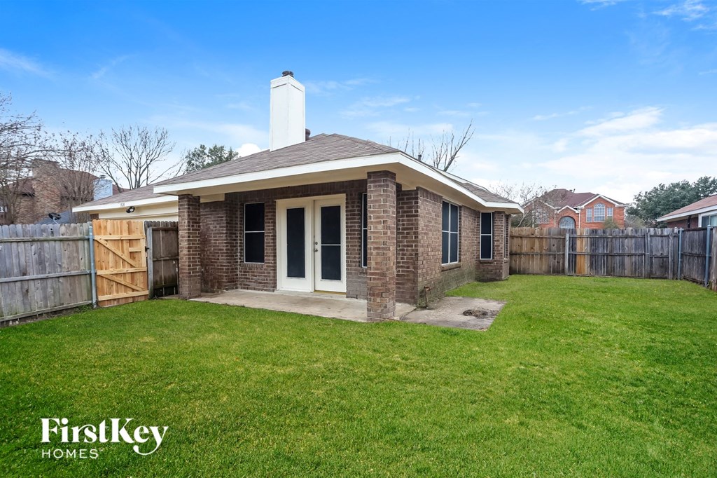 a small brick house with a yard and a fence