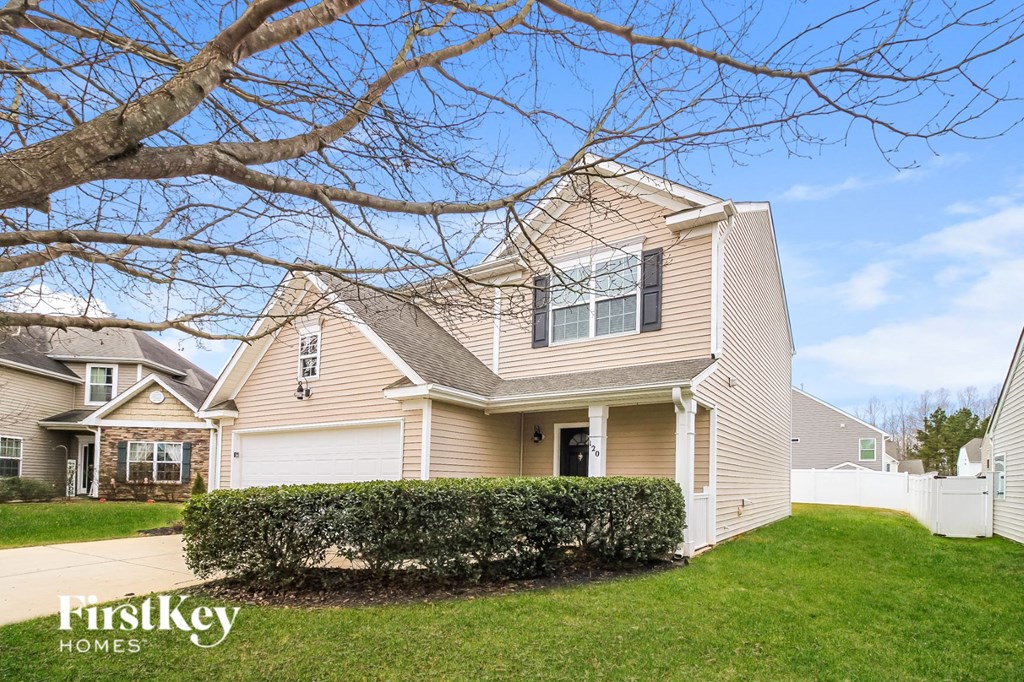 A house with a white fence and a tree in front of it.
