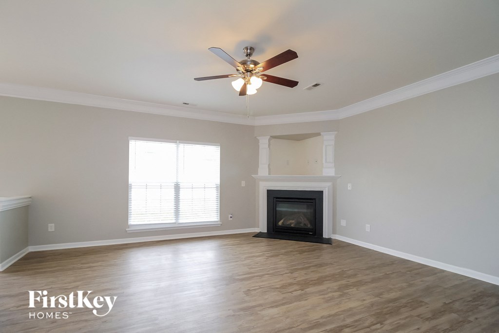 A spacious room with a fireplace and a ceiling fan.