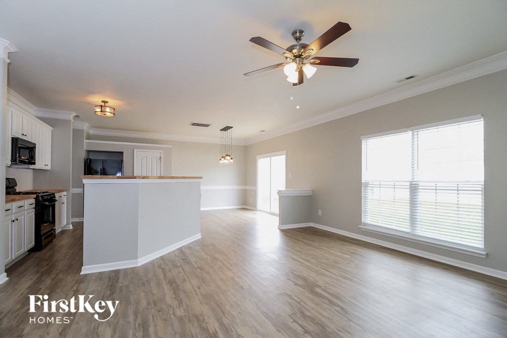 A spacious kitchen and living room with a ceiling fan and lighting fixtures.