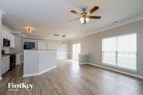 A spacious kitchen and living room with a ceiling fan and lighting fixtures.