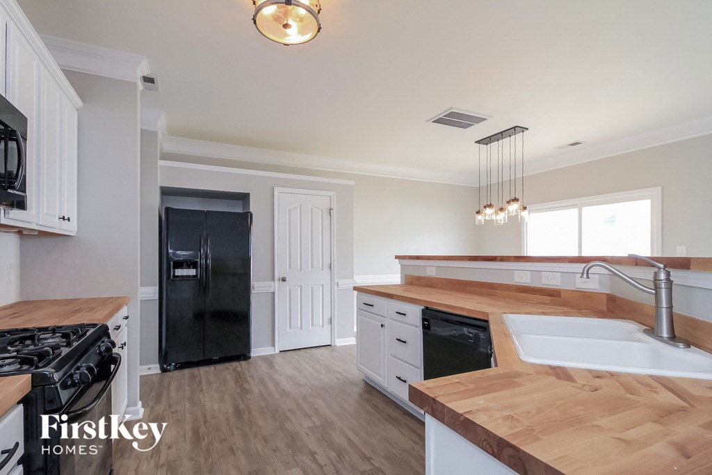 A kitchen with a black fridge and a wooden counter top.