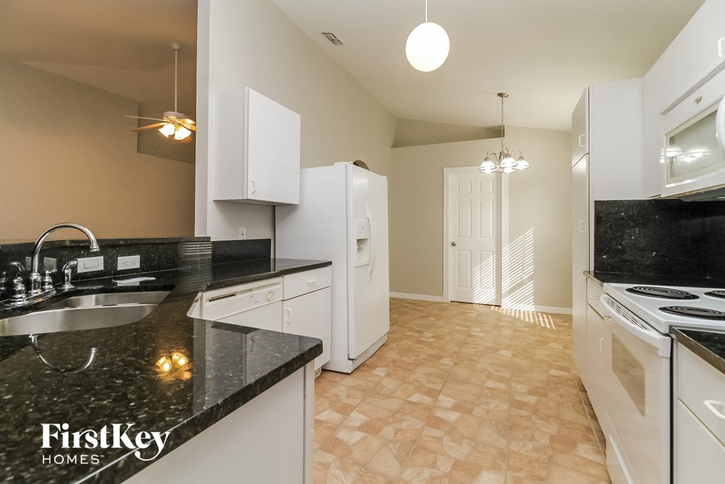 a kitchen with white appliances and black counter tops