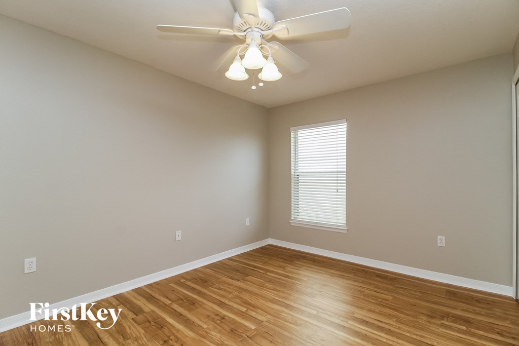 the spacious living room with a ceiling fan and wood flooring