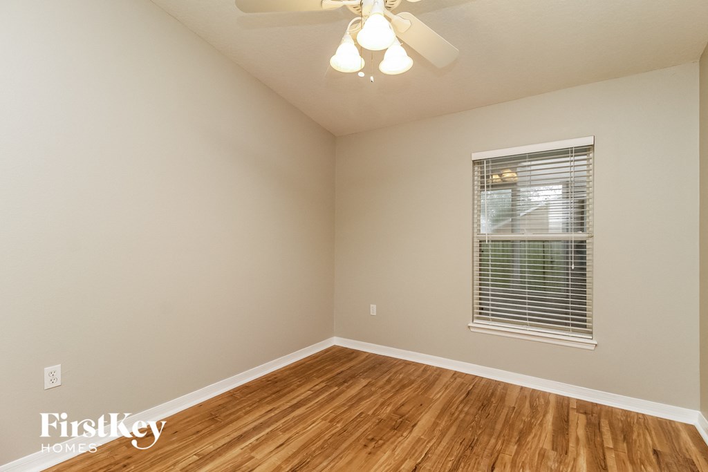 a bedroom with hardwood flooring and a window and a ceiling fan