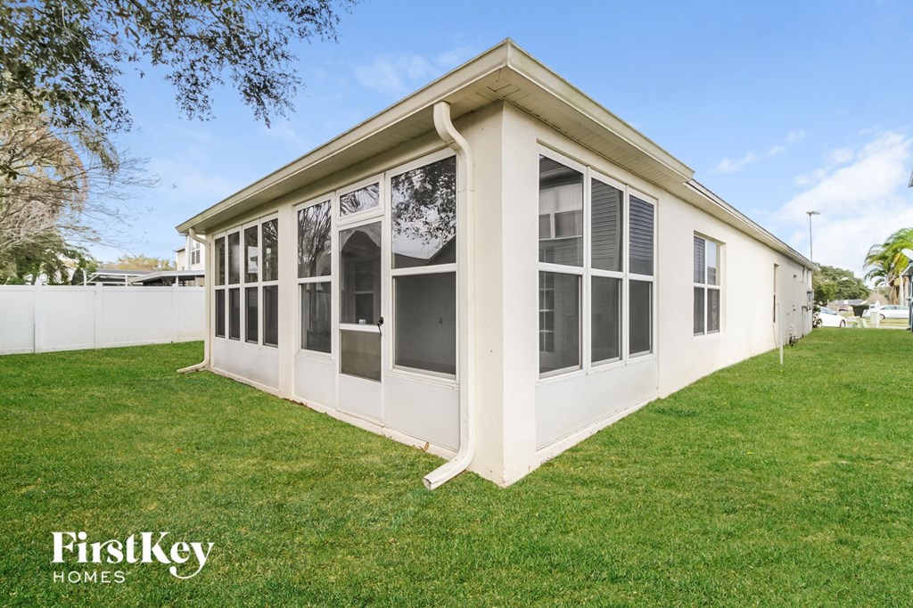 the exterior of a white house with large windows and a lawn