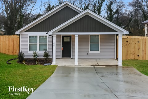 the front of a house with a driveway and a wooden fence