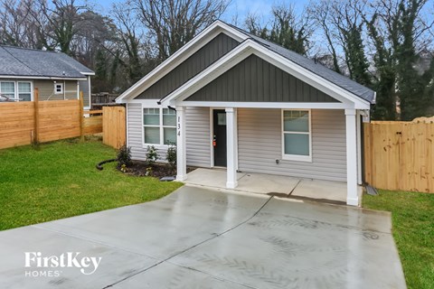 a small gray house with a porch and a wooden fence