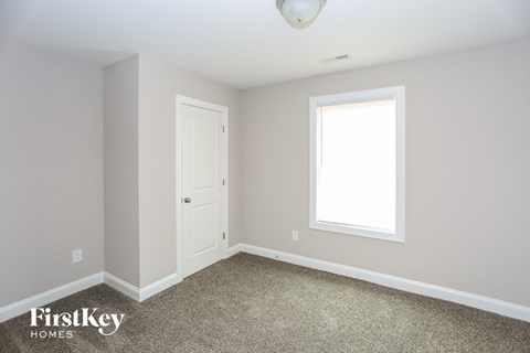 a bedroom with a white door and a window and a carpet