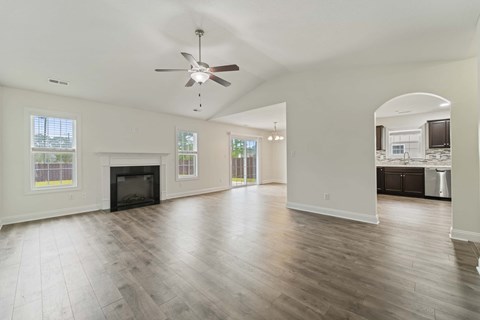 A spacious living room with a fireplace and hardwood floors.