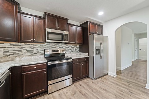 A kitchen with wooden cabinets and a stone backsplash.