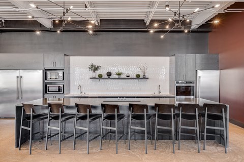 a kitchen with a large island and chairs in front of a refrigerator