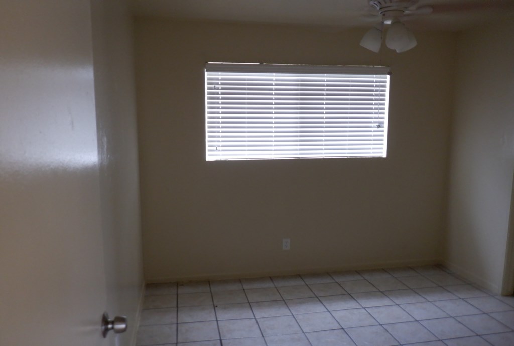 an empty room with a window and a tiled floor