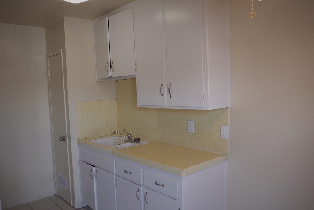 an empty kitchen with white cabinets and a sink