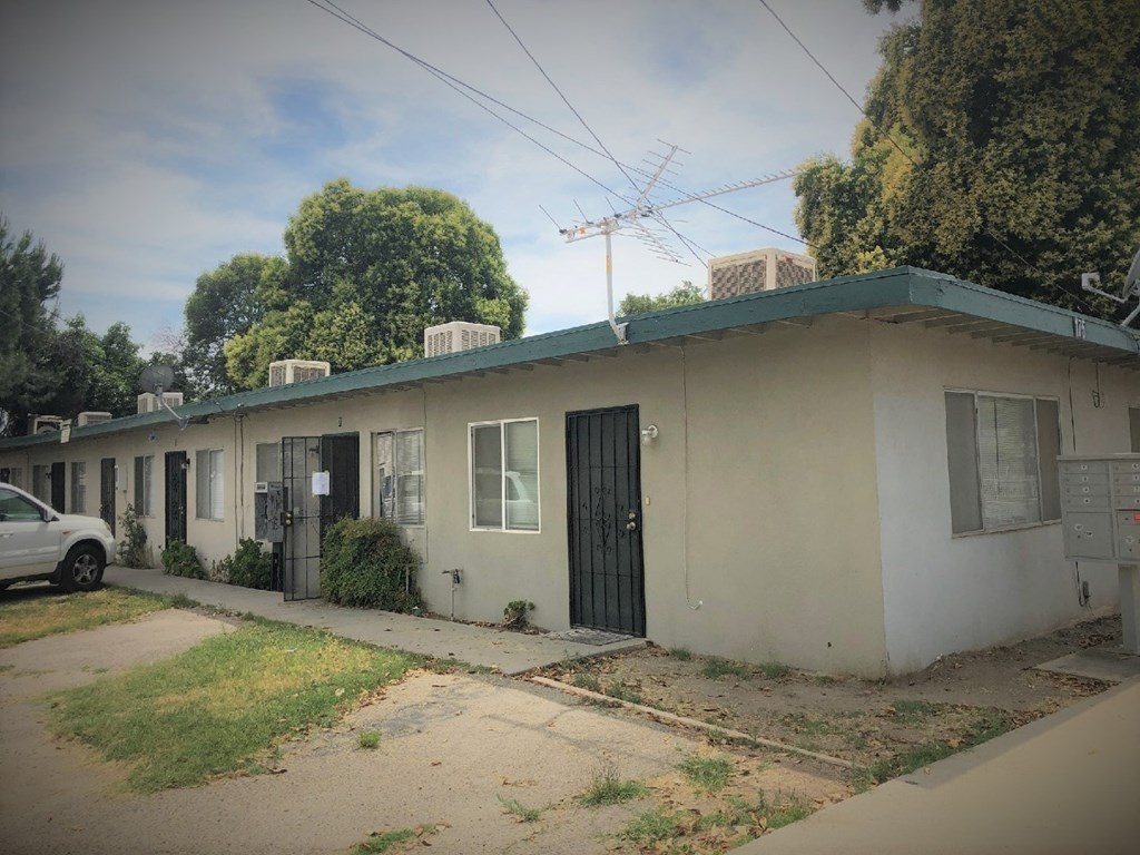 a white building with a green roof and a car parked outside