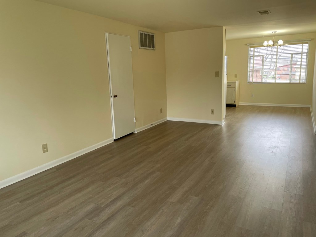 an empty living room with wooden floors and a window