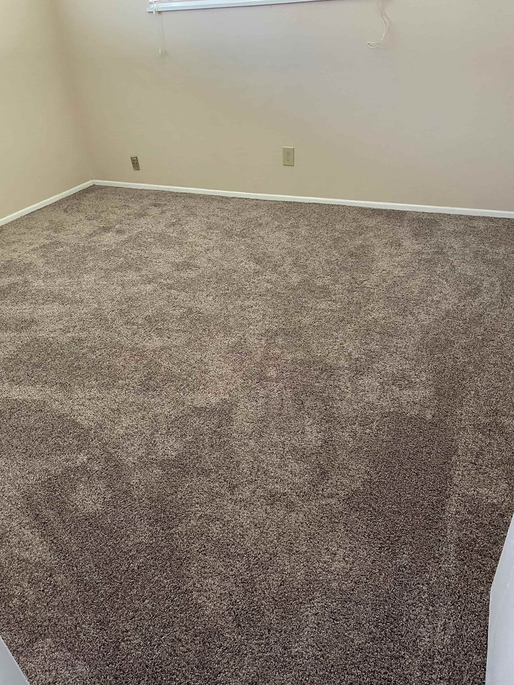 an empty room with a carpeted floor and a white wall