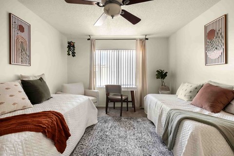 A bedroom with two beds and a ceiling fan.