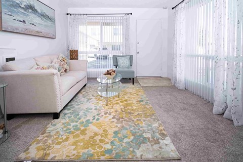 A living room with a floral rug and a white couch.