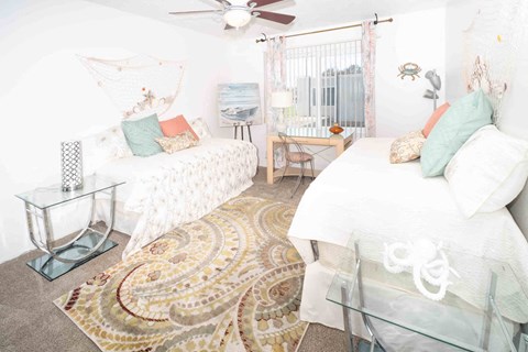 A bedroom with two beds and a rug on the floor.