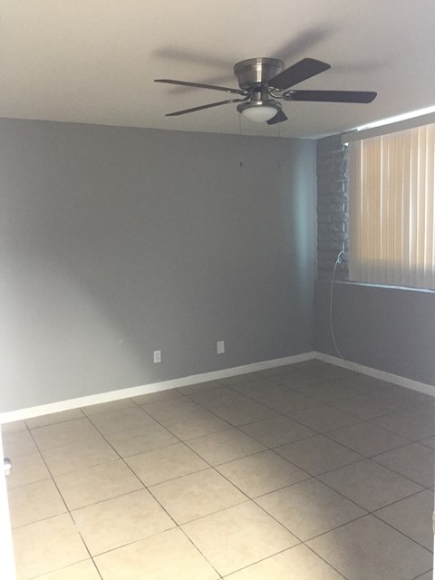 an empty room with a ceiling fan and a tiled floor
