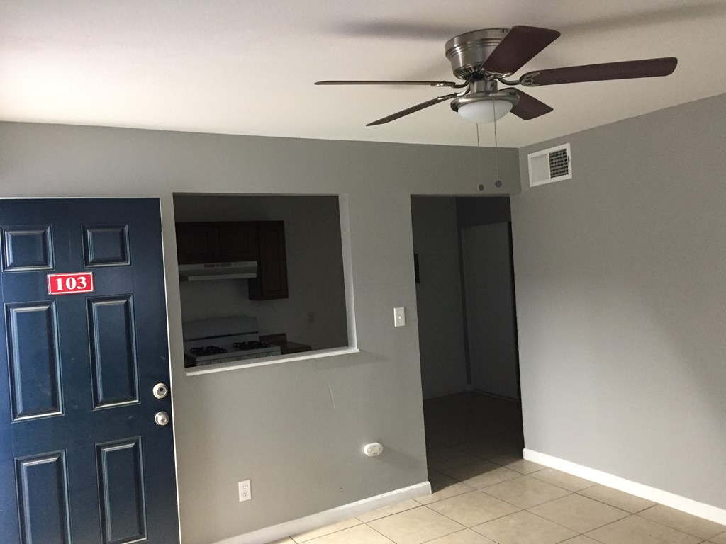 a room with a ceiling fan and a blue door