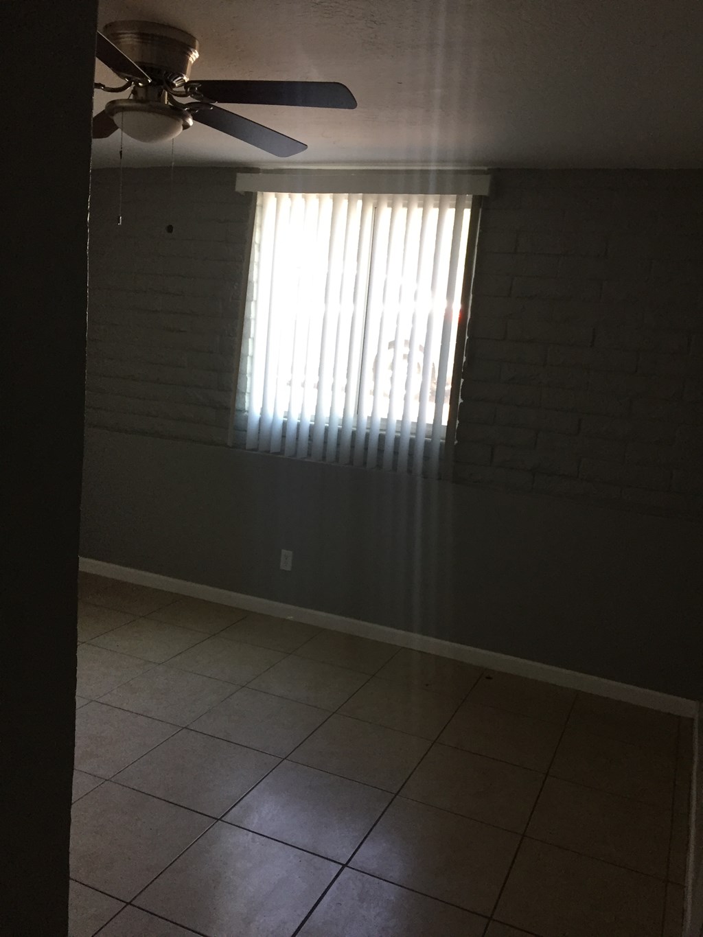 an empty room with a window and a ceiling fan