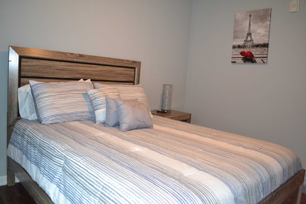 a bedroom with a bed and a painting of the eiffel tower