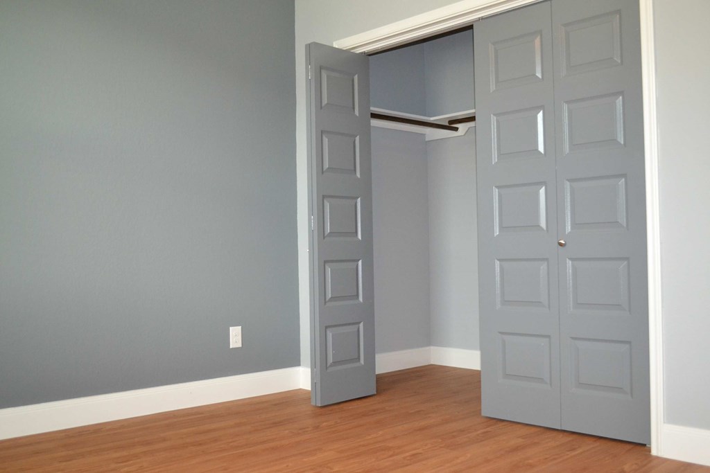 an open closet door in a room with wood floors and blue walls