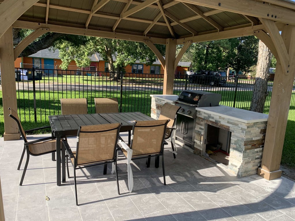 a patio with a table and chairs and a grill