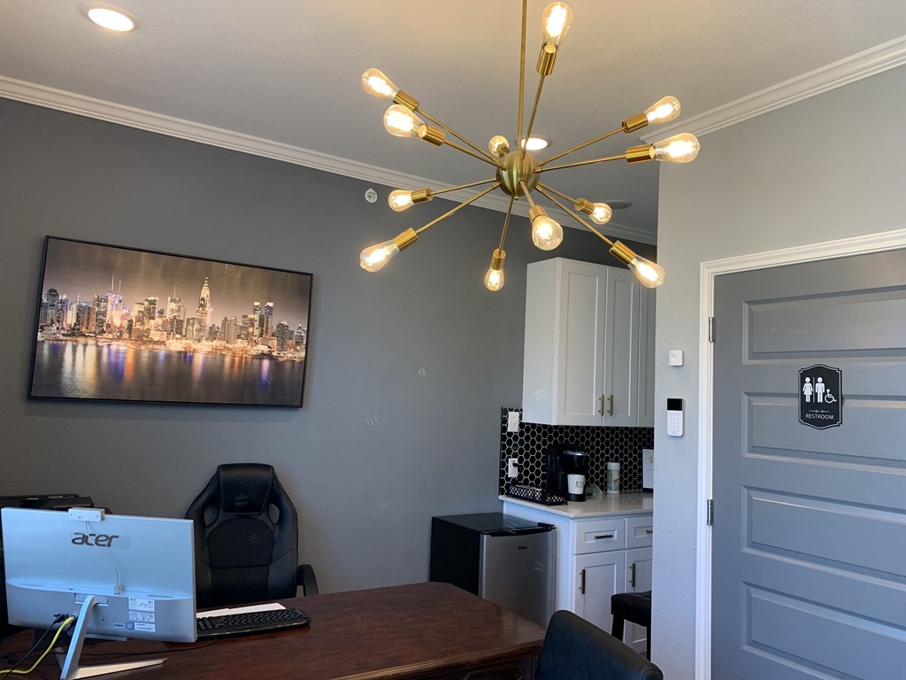 a home office with a chandelier and a desk with a computer