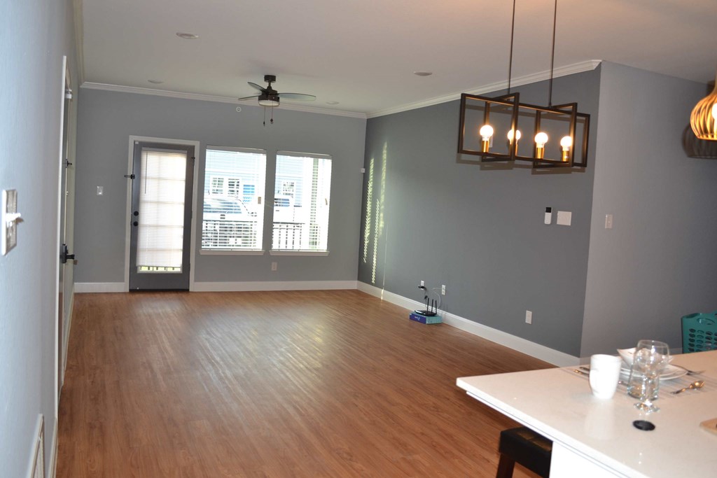 an empty living room with a wood floor and a ceiling fan