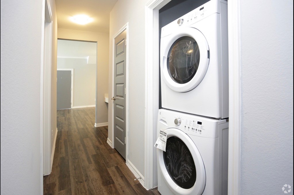 a washer and dryer in a hallway with a door to a laundry room